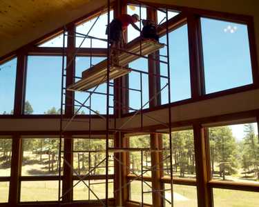 Man on tall scaffolding installing Sunglo's Window Film